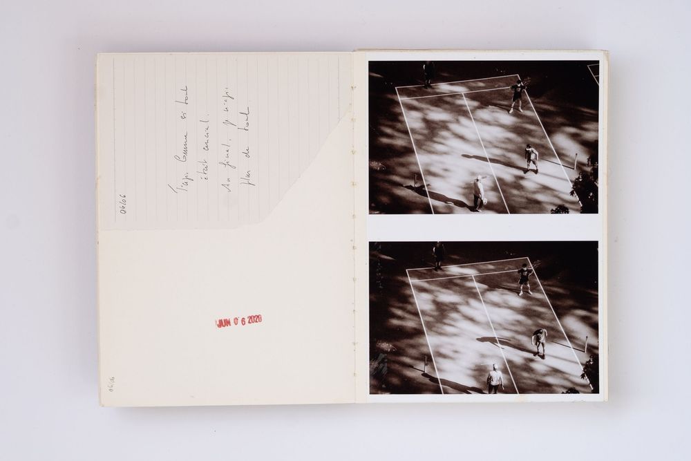 Open book with handwritten notes and two black-and-white photos showing aerial views of a sports court.