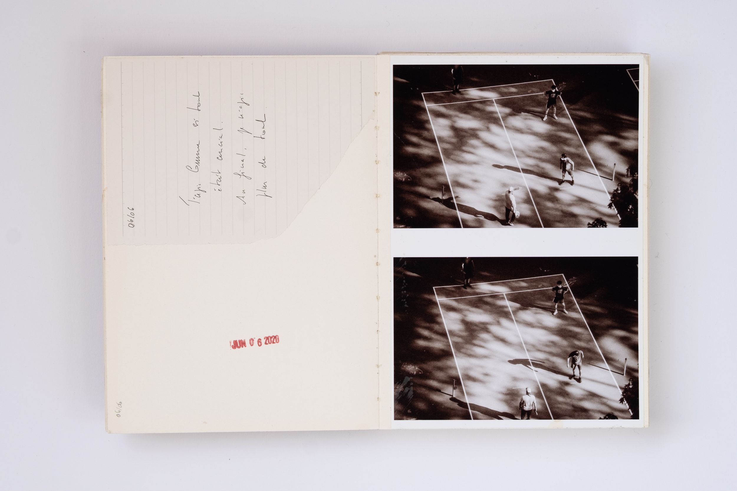 Open book with handwritten notes and two black-and-white photos showing aerial views of a sports court.