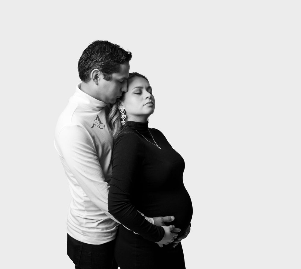 A side profile black and white maternity photo with dramatic lighting.