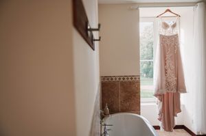 Robe de mariée suspendue près d’une fenêtre avant la cérémonie de mariage