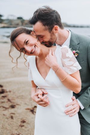 Mariés enlacés et souriants lors d’une séance photo sur la plage