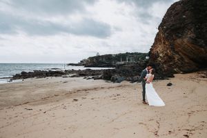Couple de mariés sur une plage sauvage en Bretagne face à l’océan
