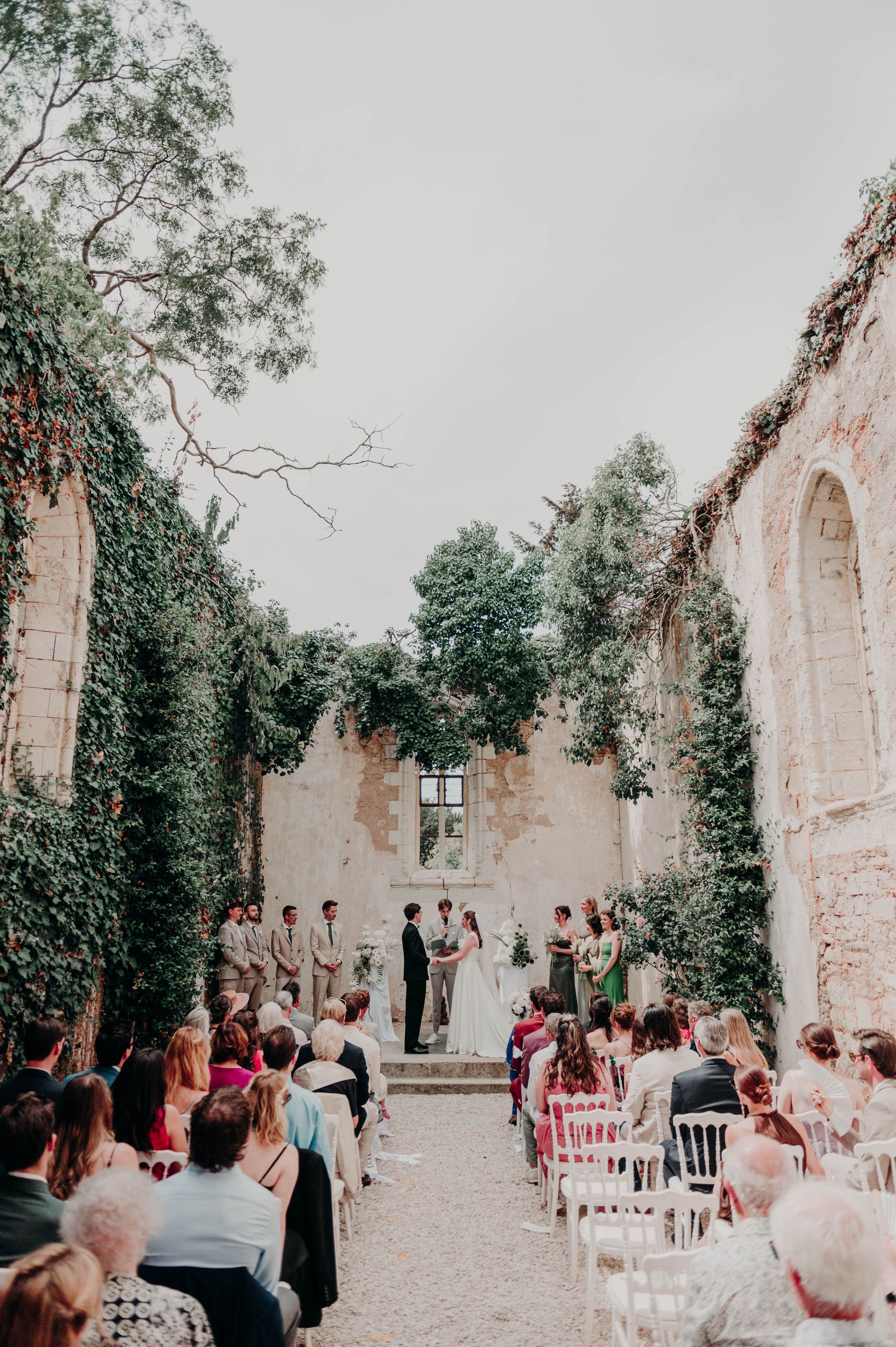 Cérémonie de mariage en extérieur dans la cour d’un domaine entouré de verdure en Bretagne.