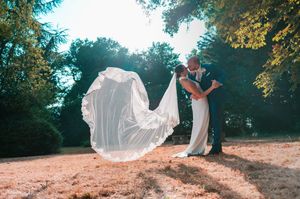 Les mariés jouant avec le voile lors de leur séance couple en pleine nature.