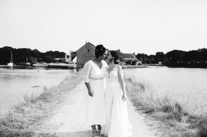 Les mariées marchant ensemble dans un champ lors de leur séance photo en noir et blanc.