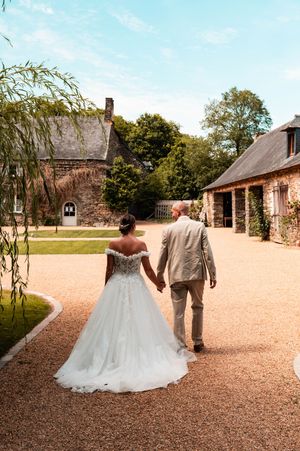 Les mariés marchant main dans la main dans la cour de leur domaine de mariage.