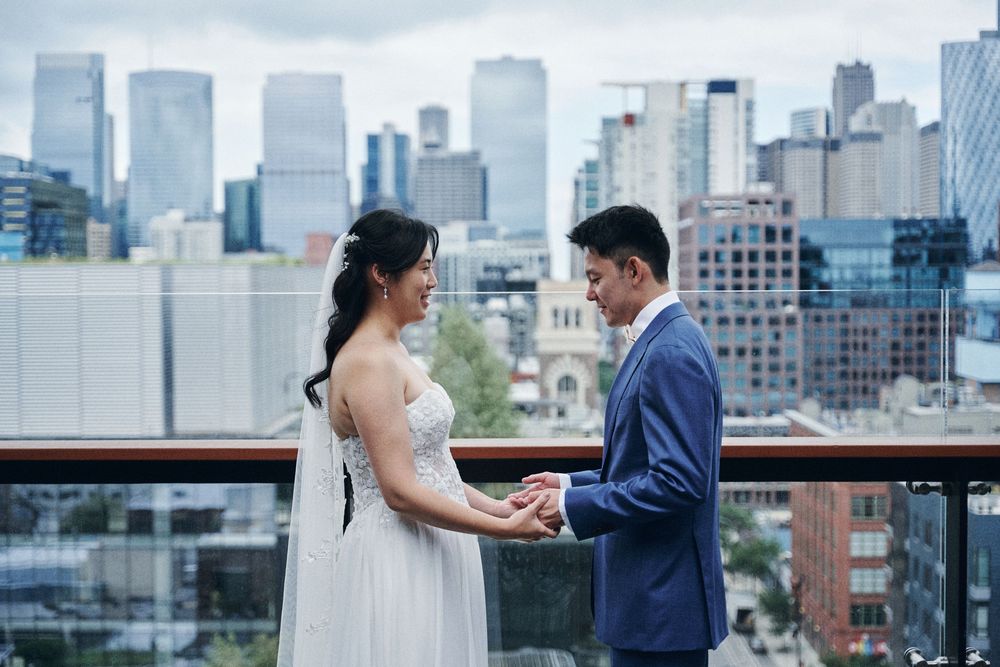 Bride and groom exchange vows on a rooftop with a stunning city skyline backdrop on their wedding day.