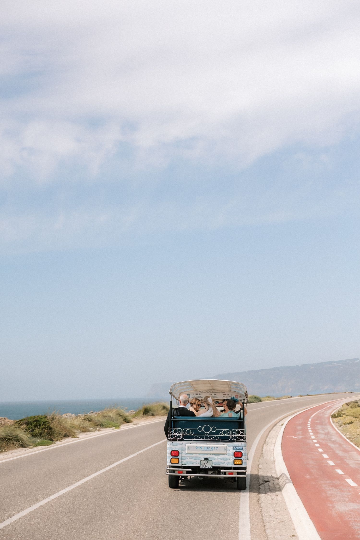 Bride arriving by tuk tuk along the Cascais coastline before her destination wedding overlooking the Atlantic Ocean.