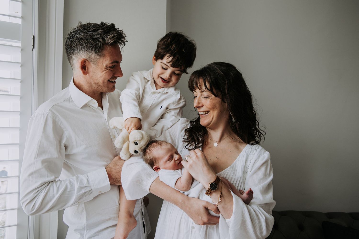 Parents and toddler cuddling their newborn baby together during a relaxed family newborn photography session in Somerset.
