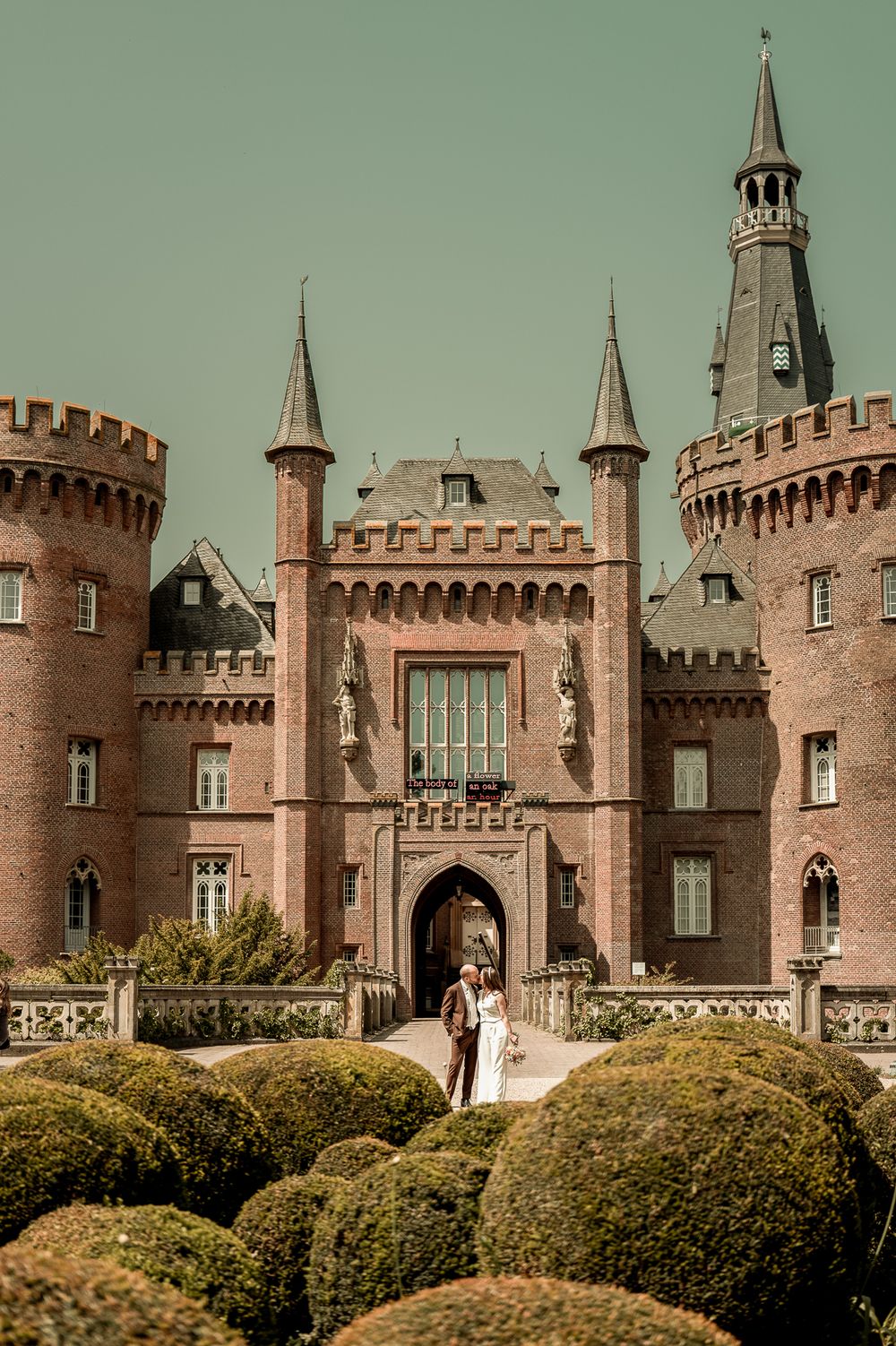 Brautpaar vor der beeindruckenden Architektur von Schloss Moyland, Hochzeitsfotografie NRW.