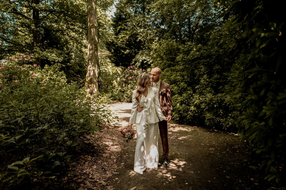 Brautpaar umarmt sich in der Allee am Schloss Moyland, authentische Hochzeitsfotos.