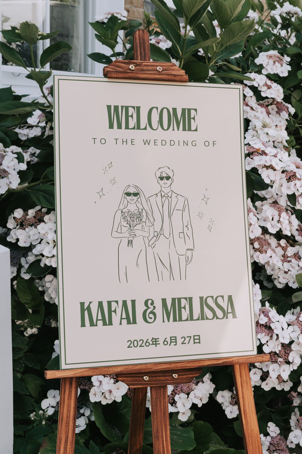 Wedding welcome sign on easel for Kafai and Melissa, June 27 2026, with couple illustration and floral backdrop.