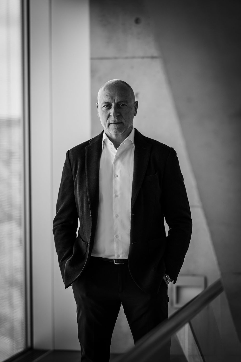 Schwarz-weißes Businessporträt eines Mannes mit Händen in den Hosentaschen und direktem Blick in die Kamera. GELSEN-NET.