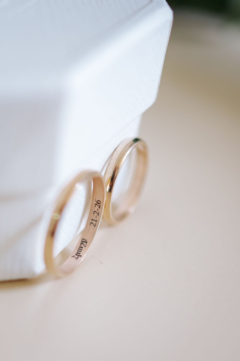 Close-up of engraved gold wedding bands resting on white ring box.