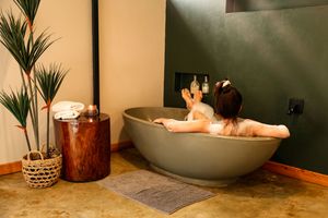 Woman relaxing in a freestanding stone bathtub in a Boutique Unique Stay.