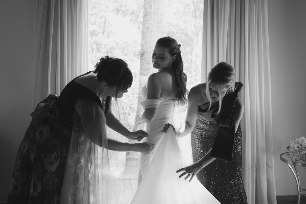 mãe e irmã da noiva arrumando o vestido