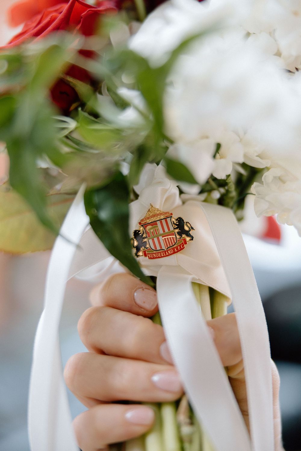 Bride holding a bouquet of red and white flowers with a Sunderland AFC crest ribbon.