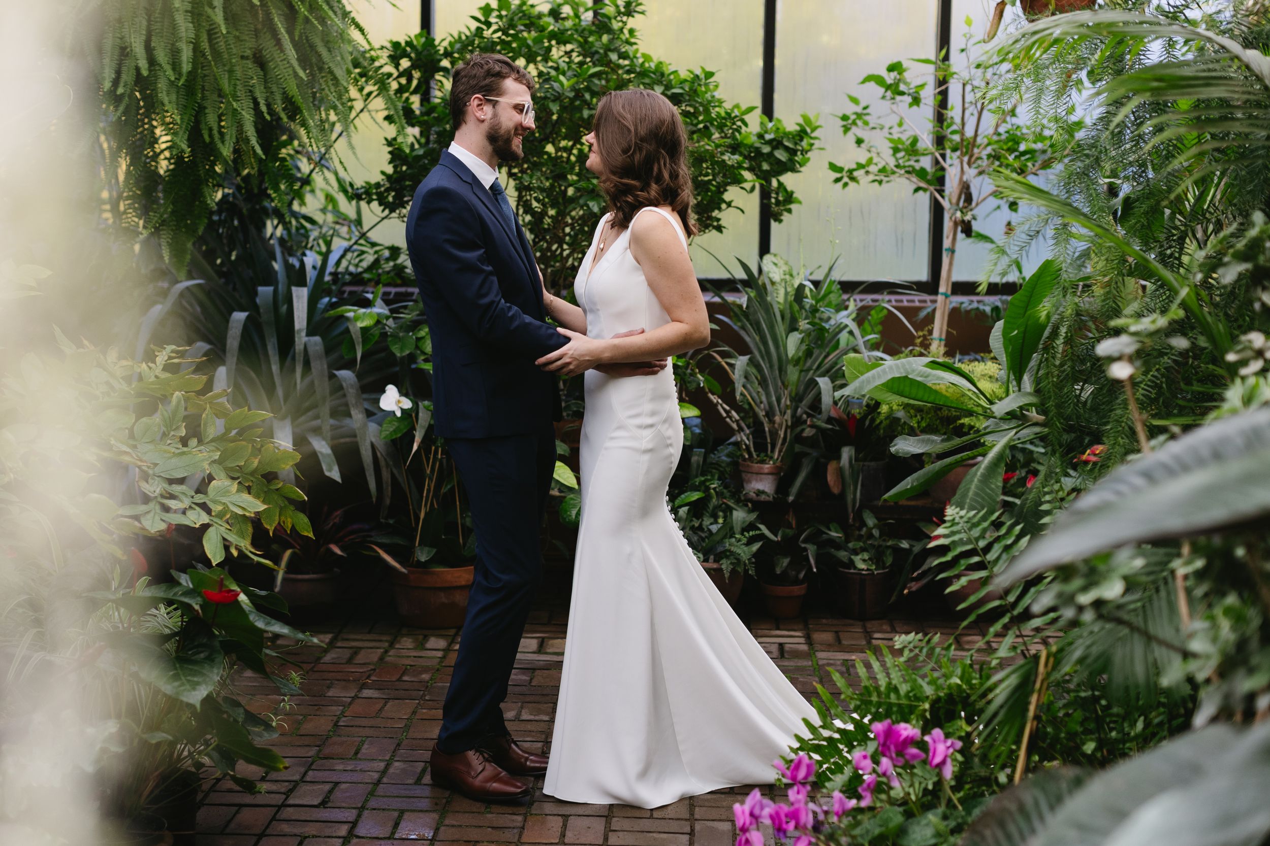 A romantic wedding moment between a couple in an intimate garden setting with lush greenery and flowers. Twin Cities wedding photography.