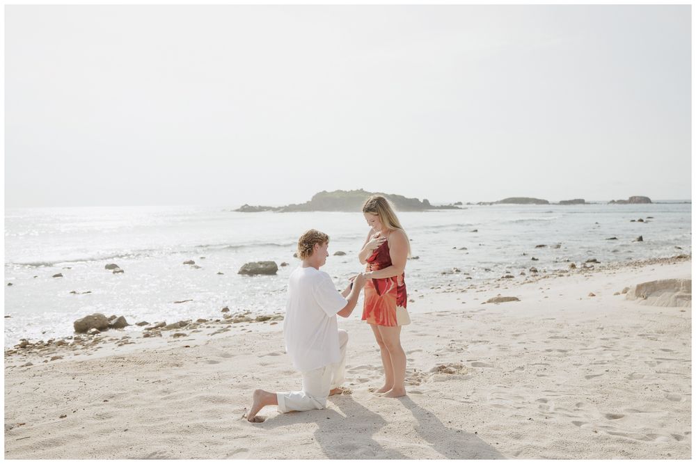 Punta Mita Engagement Session featuring a Groom proposing to his fiancée on a sandy beach by the ocean.
