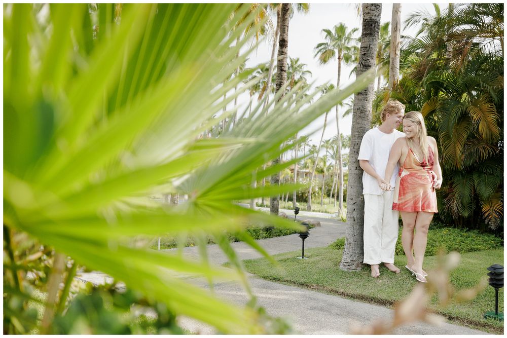 Punta Mita Engagement Session featuring a couple embracing among lush tropical palm trees in a resort garden.