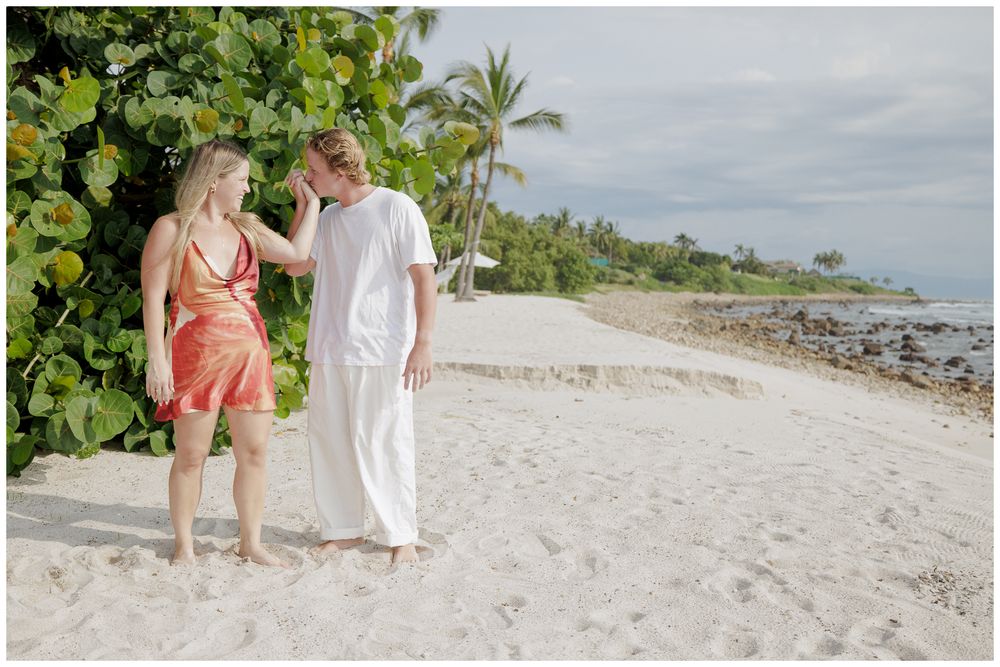 Punta Mita Proposal Photography featuring a couple walking hand in hand along a sandy beach lined with tropical palm trees.