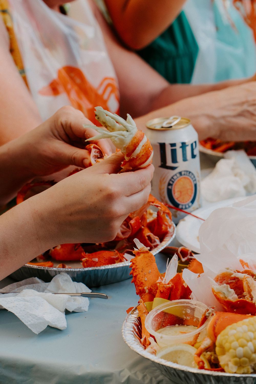 Guests crack open fresh lobster beside a Miller Lite can at an outdoor seafood wedding reception.