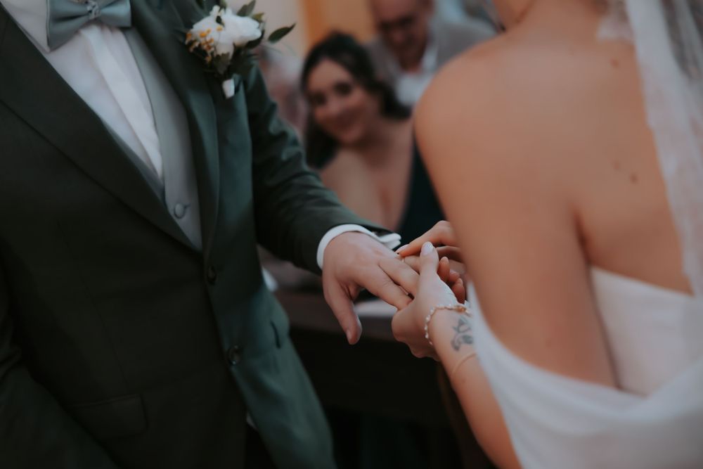 Groom placing a wedding ring on brides finger during an elegant wedding ceremony.