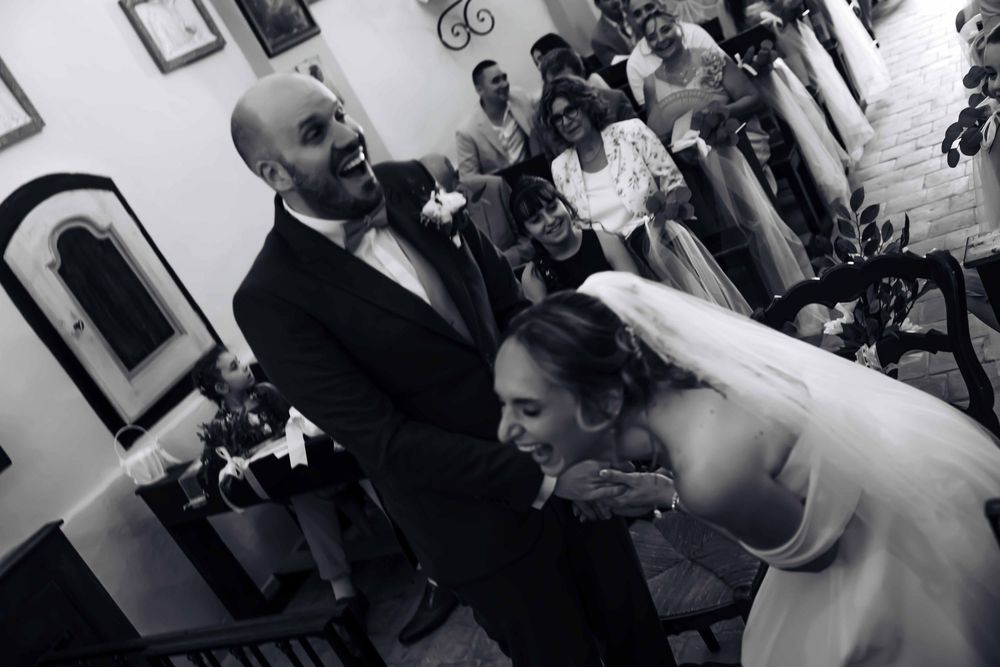Bride kisses groom's hand at altar during wedding ceremony in black and white photo.