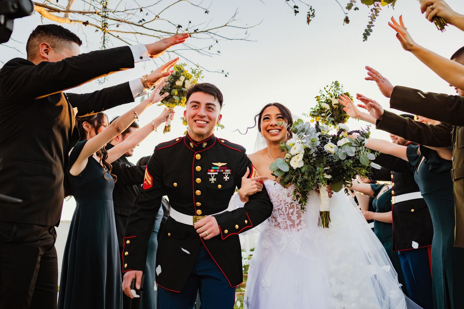 A military wedding celebration with raised swords forming an archway for the newlyweds.
