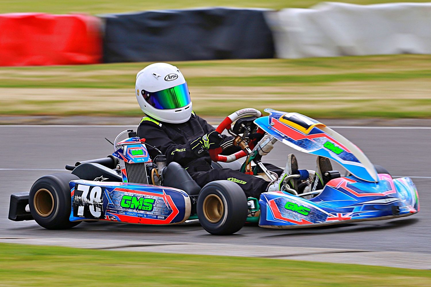 Go-kart racer number 78 in a colorful blue and green GNS kart speeding around a racing circuit.