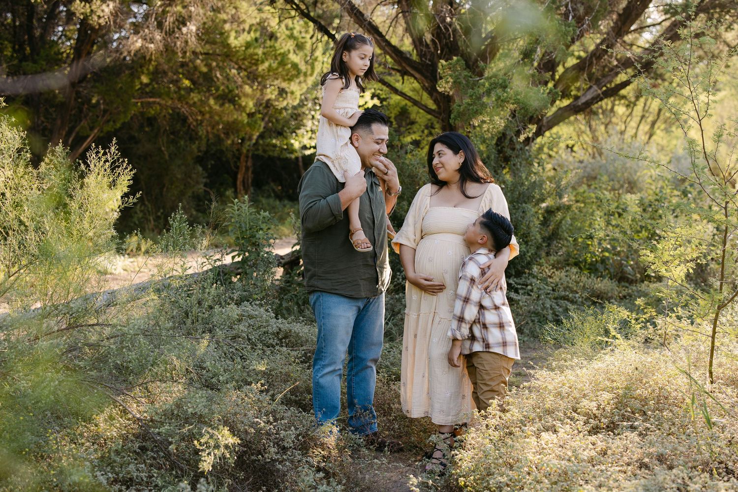 Family of four walking hand-in-hand through a sunny Mediterranean-style courtyard with arched walls.