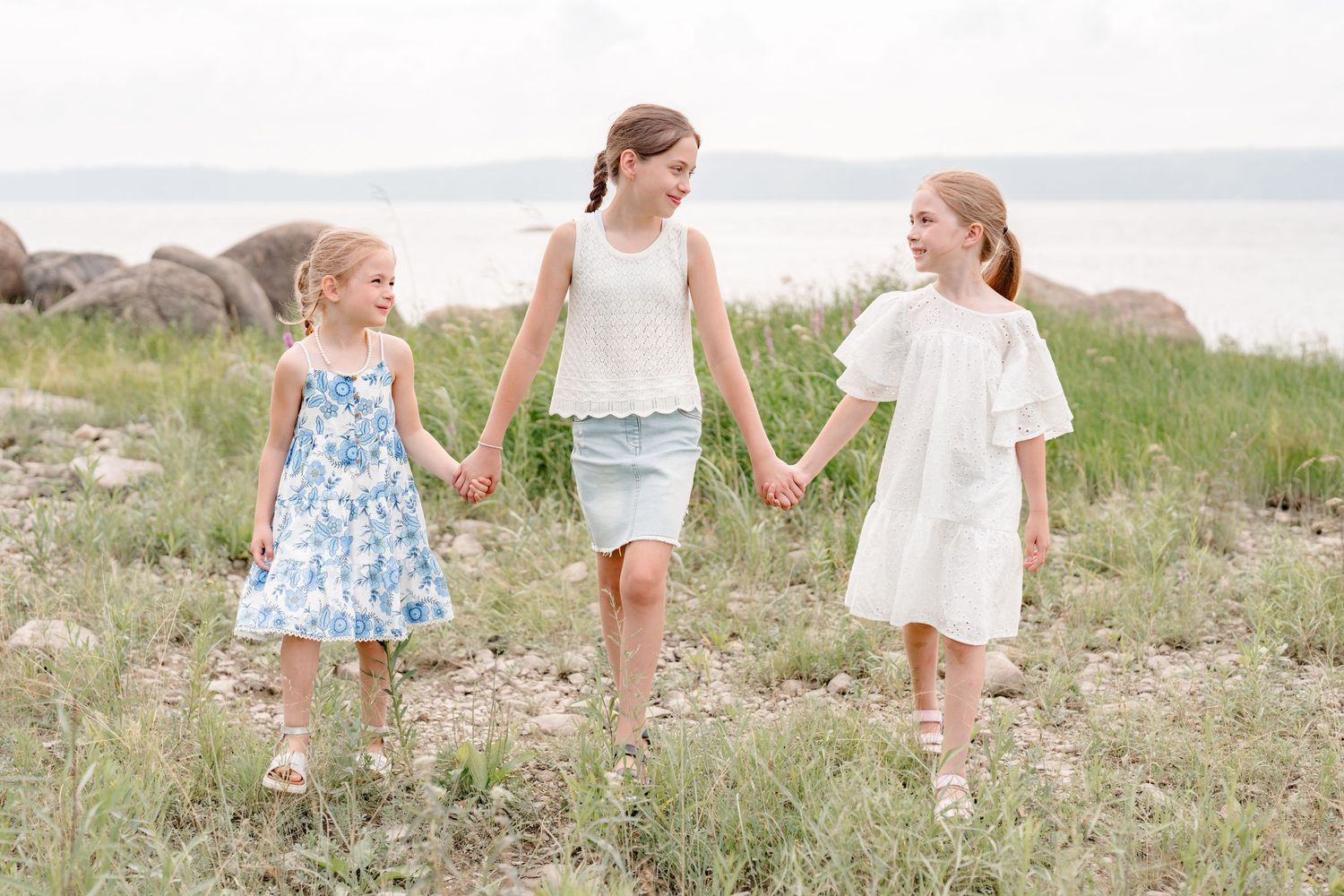 Trois soeurs se tenant par la main au bord du fleuve Saint-Laurent