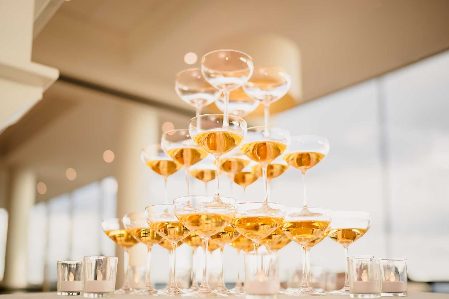 Elegant champagne tower with golden bubbly filled coupe glasses stacked in pyramid formation at the luxury the view venue