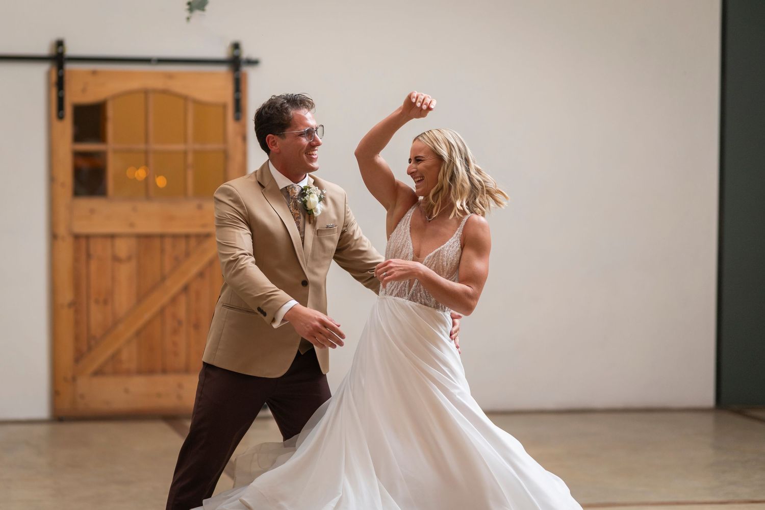 Bride and groom share a joyful first dance in a rustic barn wedding venue.