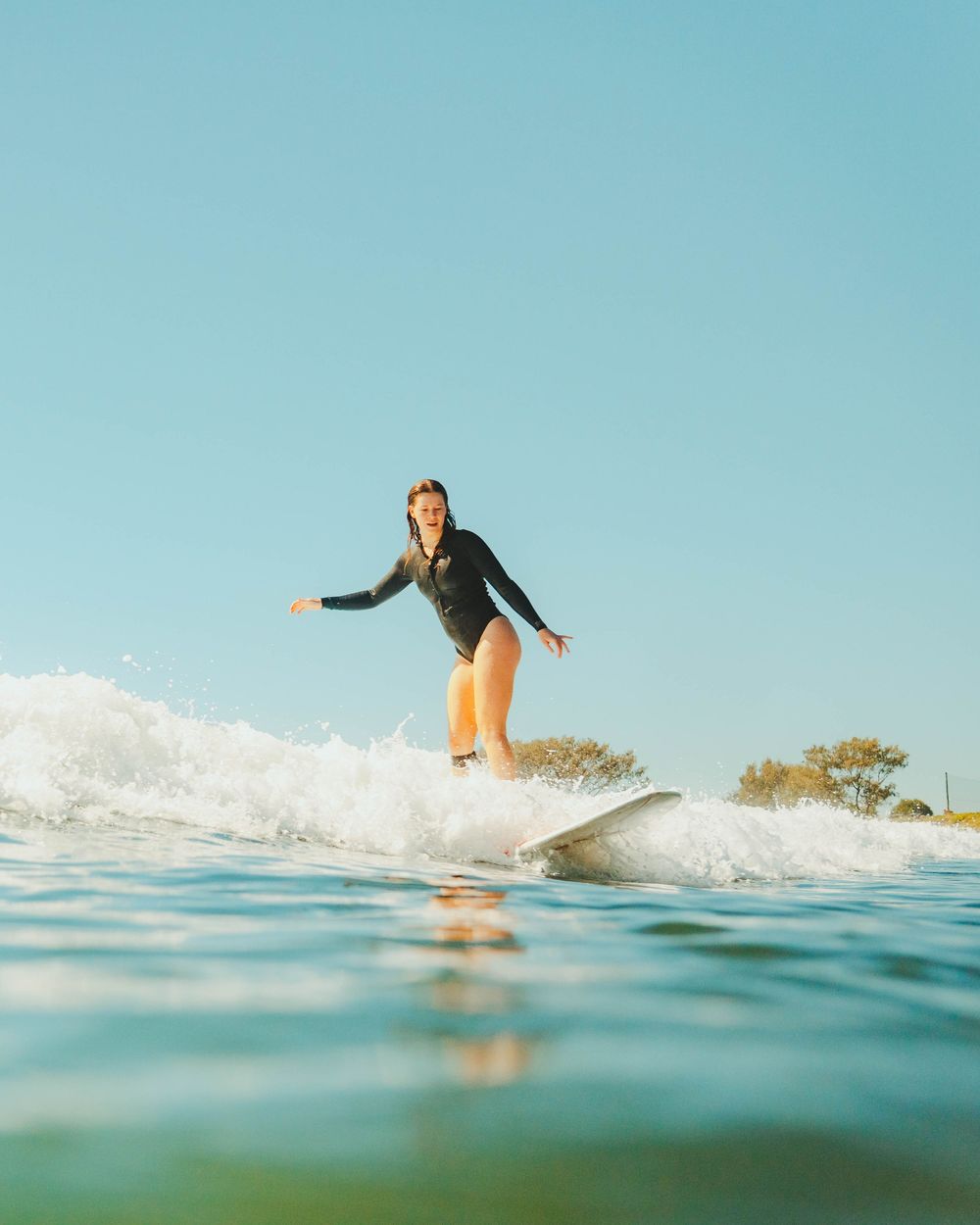 Girl smiling happily on a wave with Sunlight surfers Newcastle women's surfing group at Crescent Head Surf Camp out