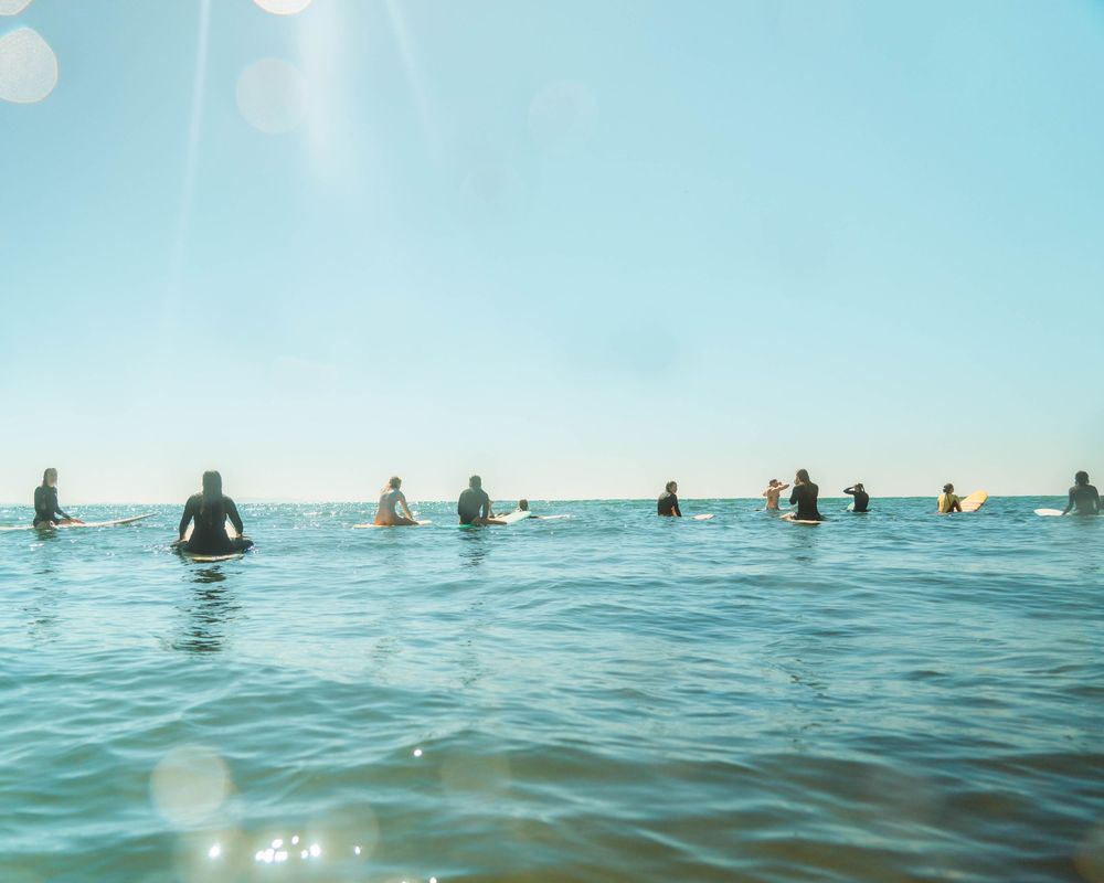 a group of women surfers all on the ocean looking out over the horizon for approaching waves at Crescent Head NSW with Sunlight Surfers