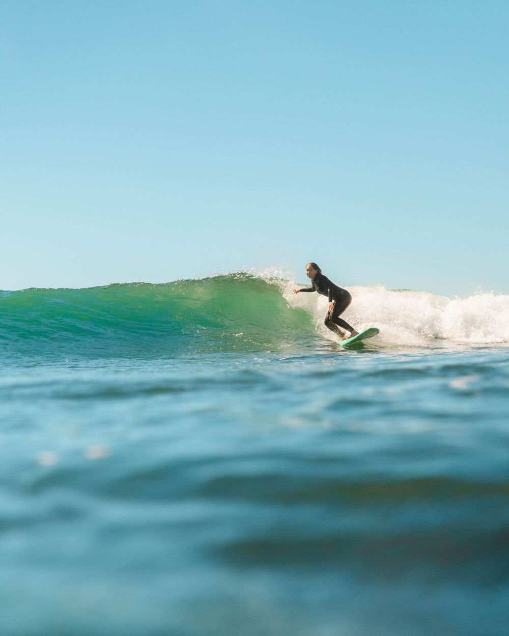 Girl doing a bottom turn on a wave with Sunlight surfers Newcastle women's surfing group at Crescent Head Surf Camp out