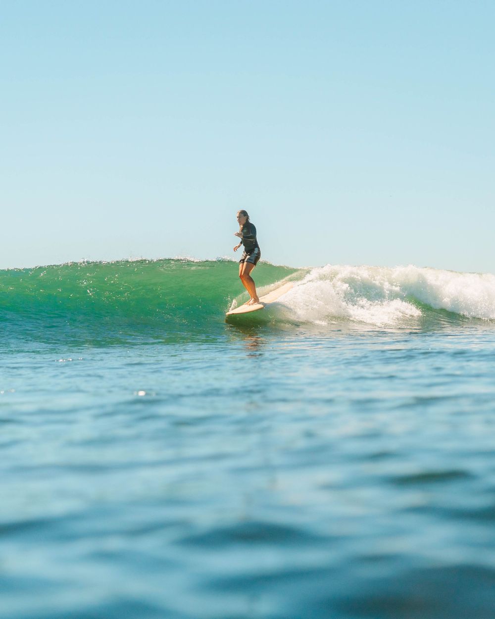 Girl smiling on a longboard point break with Sunlight surfers Newcastle women's surfing group at Crescent Head Surf Camp out