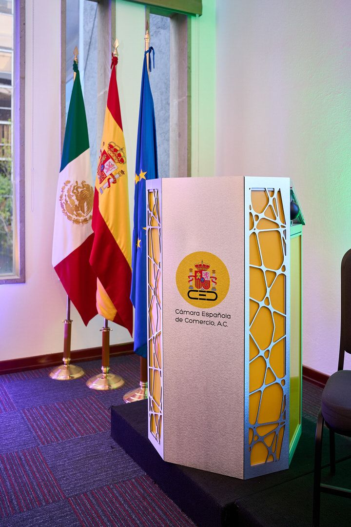Podio y banderas de México, España y Unión Europea en la Cámara Española de Comercio en México