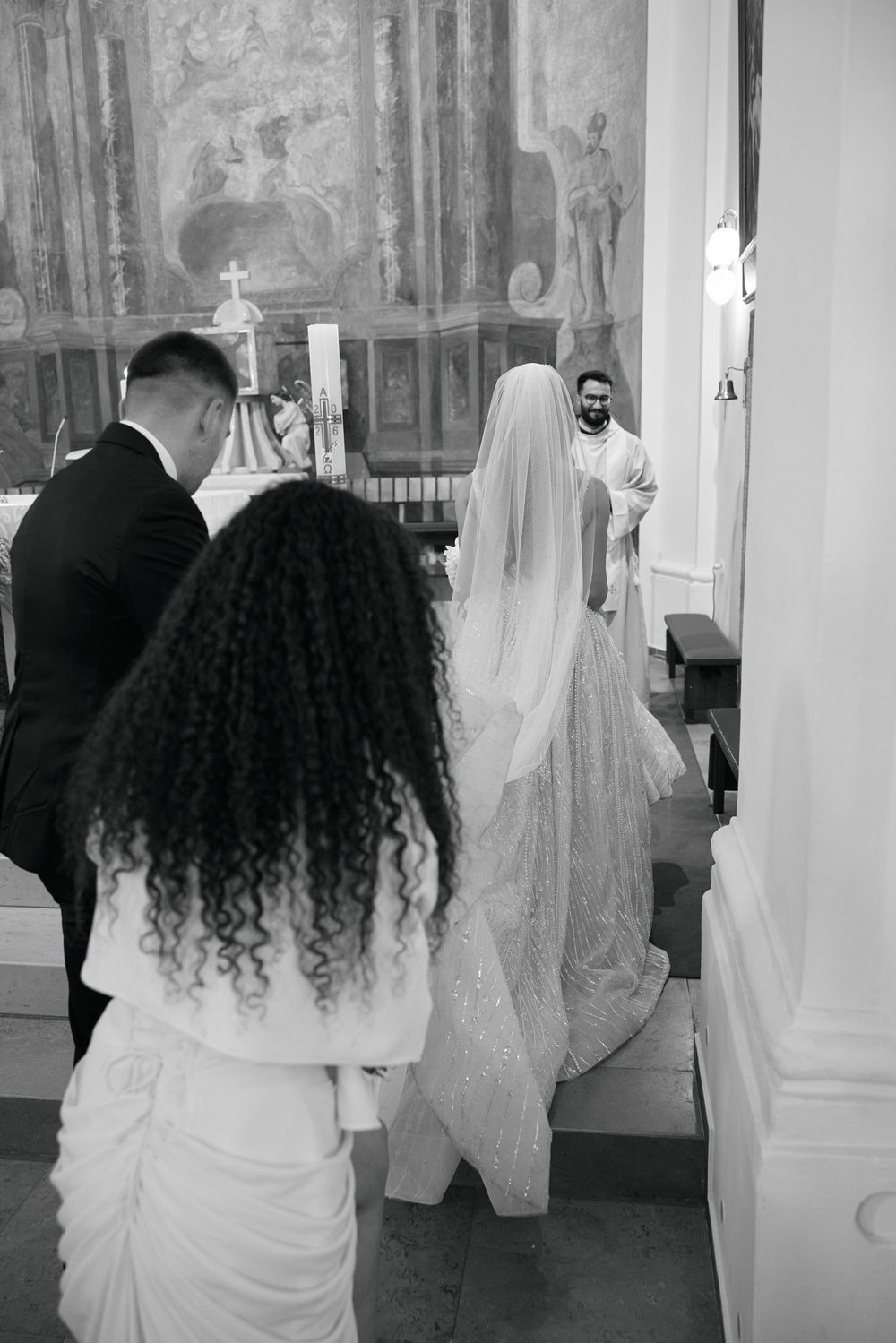 Black and white photo of bride and groom at church altar during wedding ceremony.