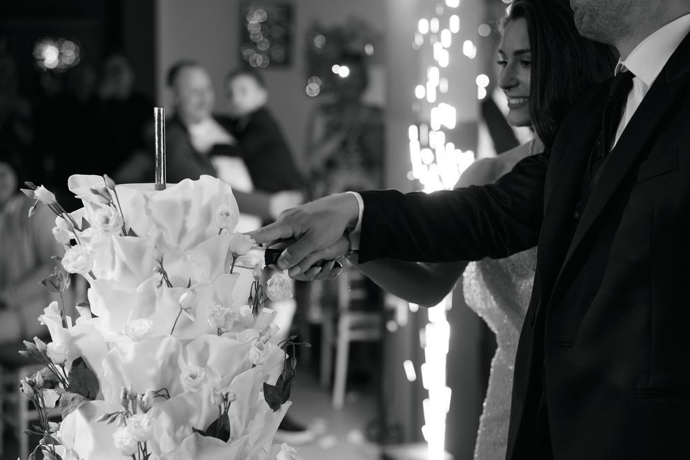 Bride and groom cutting their wedding cake together at an elegant reception venue in black and white.