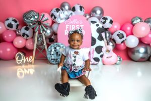 Baby's first birthday cake smash with pink balloons, disco balls, cow print decor, and a guitar in a festive studio setting.