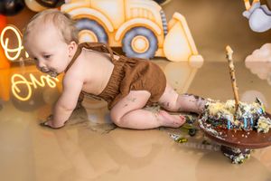 Baby in brown bloomers doing a cake smash at a construction-themed first birthday party.