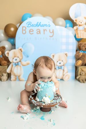 Baby boy smashes blue teddy bear first birthday cake at Beckham's Beary First Birthday party celebration.