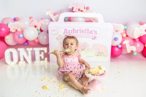 Happy baby girl messily enjoys cake smash at Aubriella's pink ONE first birthday balloon photo session.