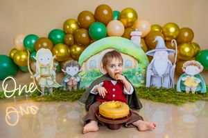 Baby's first birthday cake smash with Lord of the Rings theme, balloons, and character cutouts.