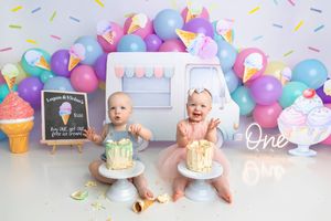 Twin babies celebrate their first birthday with ice cream themed cake smash, colorful balloons, and pastel decorations.