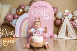 Baby girl celebrates her first birthday with a pink ONEderful cake smash backdrop, balloons, and teepee decor.
