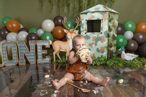 Baby's first birthday cake smash with woodland theme, deer decor, balloons, and ONE sign.