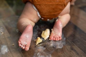 Close-up of baby feet covered in cake frosting during a first birthday smash cake photo session.